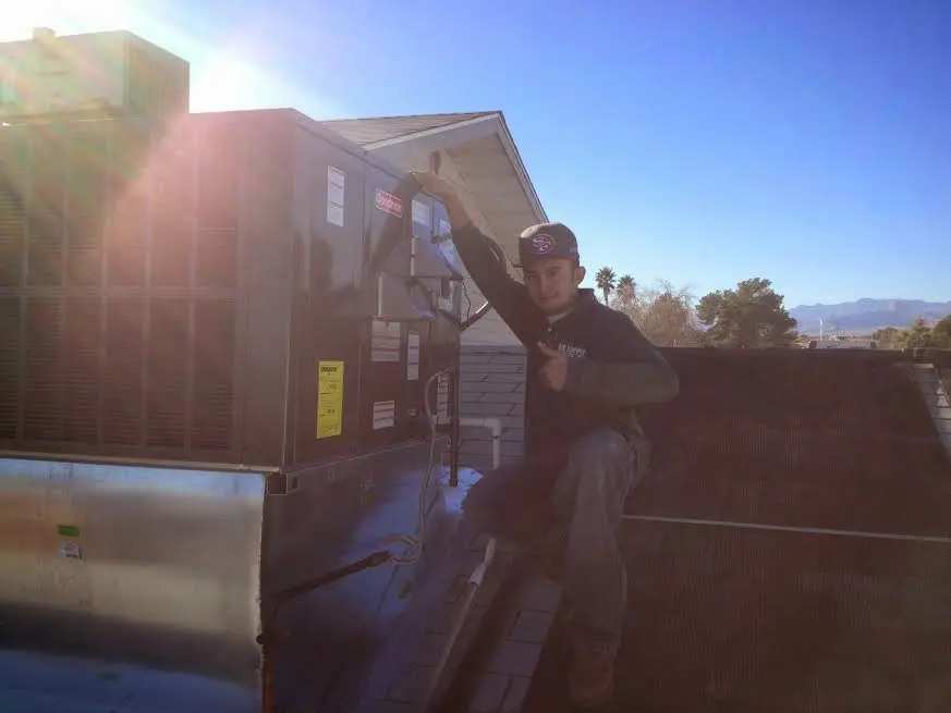 HVAC technician performing AC Tune-Up on a rooftop unit in Fort Lee